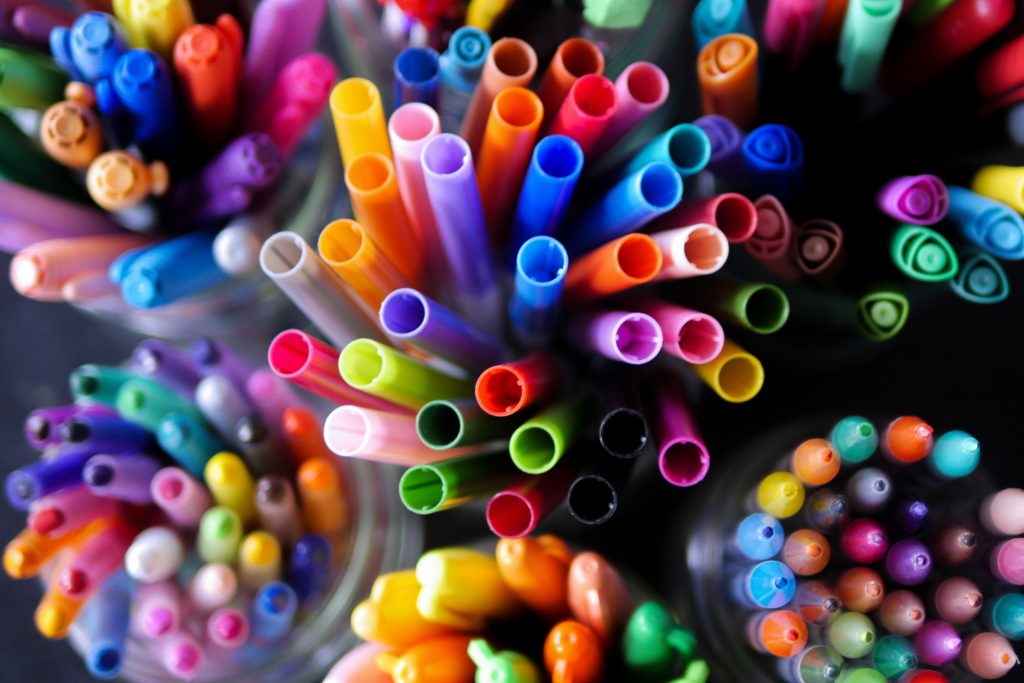 Bird's eye view of assortment of markers in different colors and containers. 