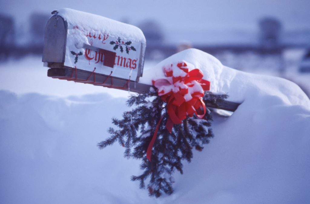 Mailbox partially covered by snow with the words Merry Christmas just visible. 